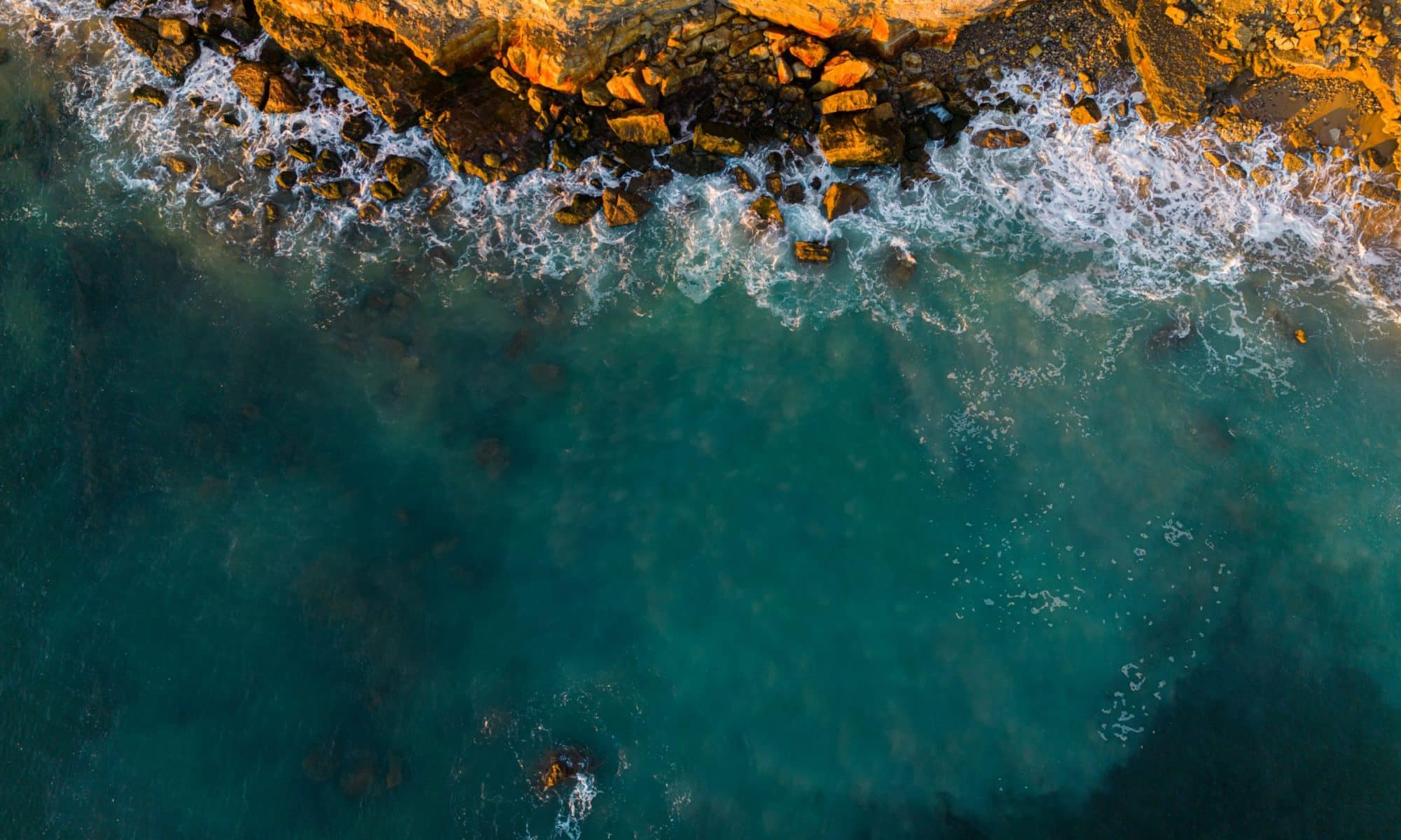 Aerial spectacle: Waves crashing on rocky cliffs in Portugal.